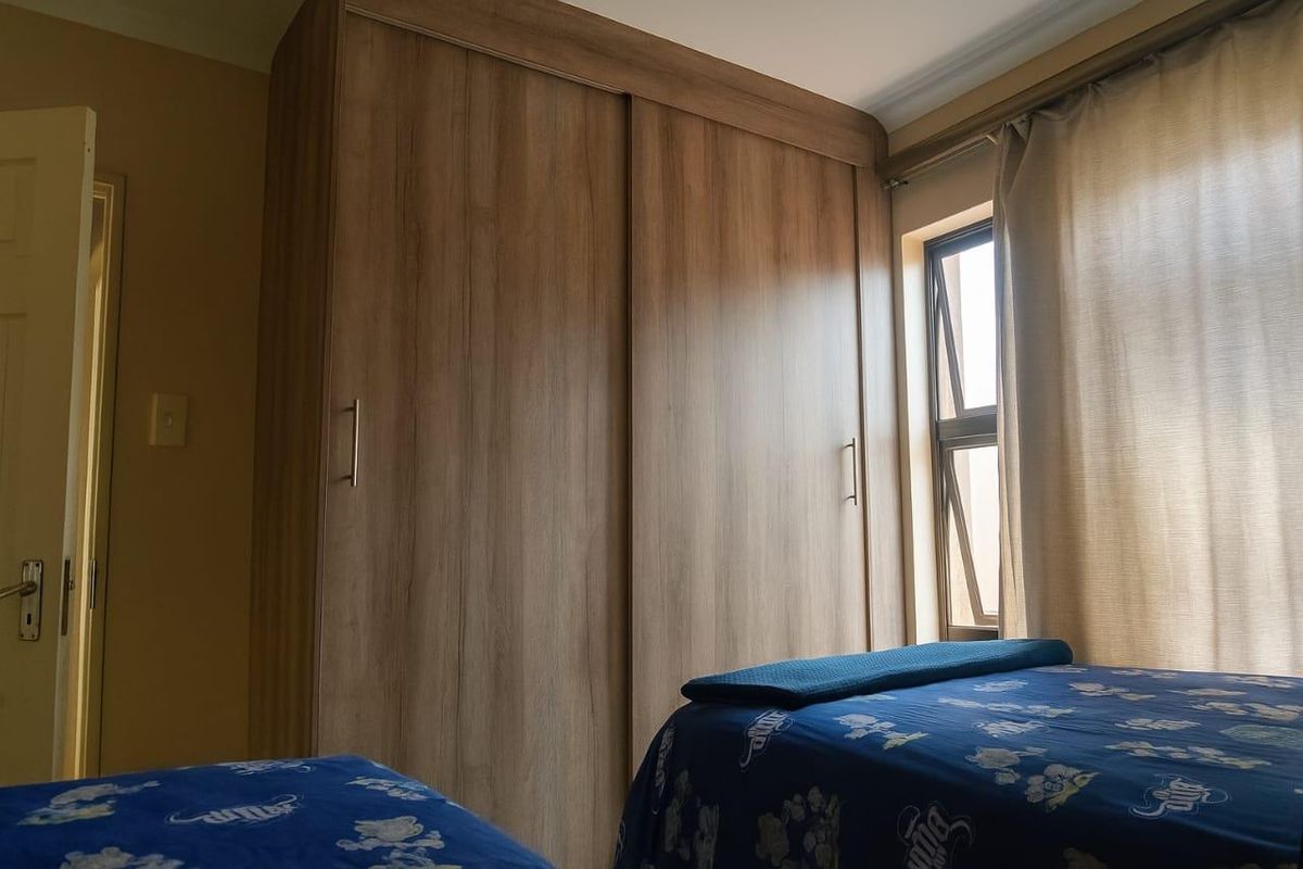 A bedroom featuring a large, modern wood-finish built-in wardrobe and a functional casement window.