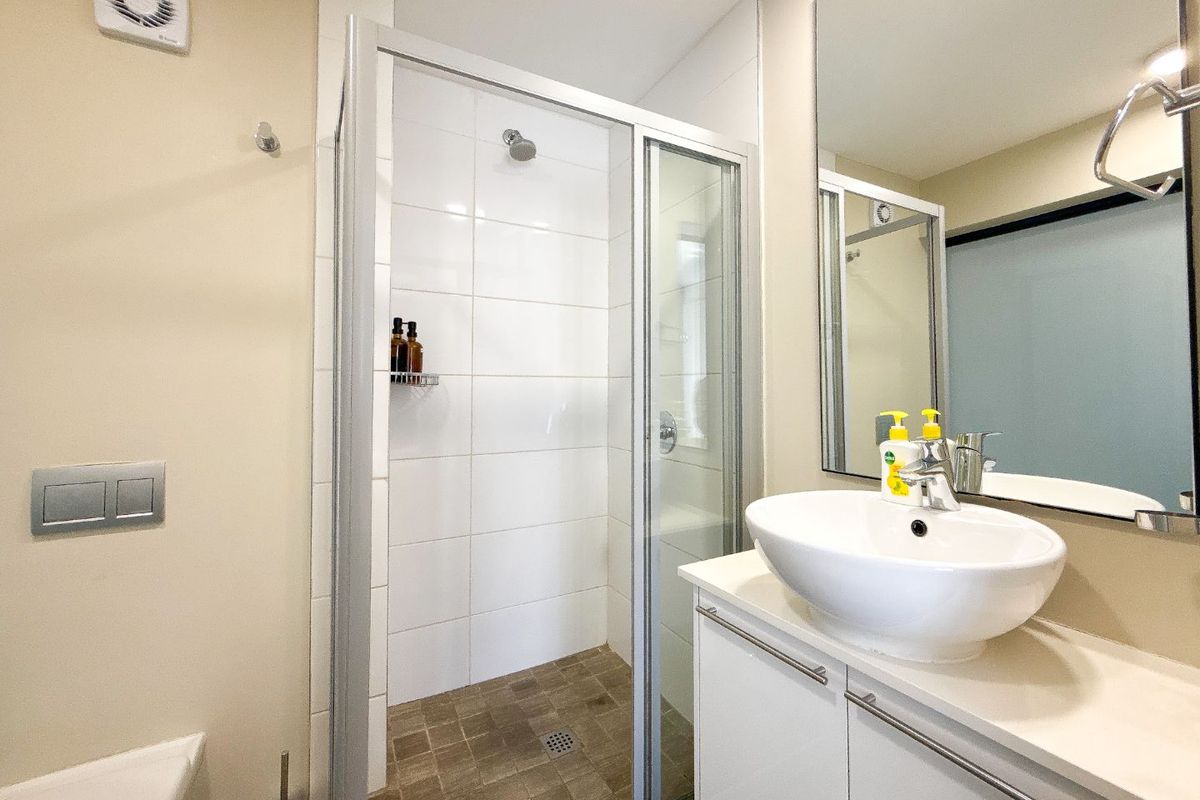 A clean, functional bathroom featuring a glass-enclosed shower, a modern vessel sink vanity, and a wall-mounted mirror.