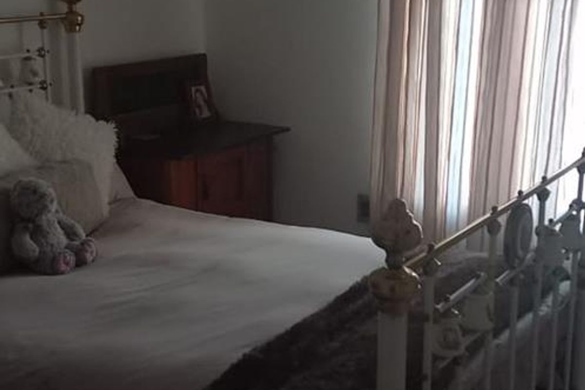 A bedroom featuring a window with curtains and a ceiling light fixture.