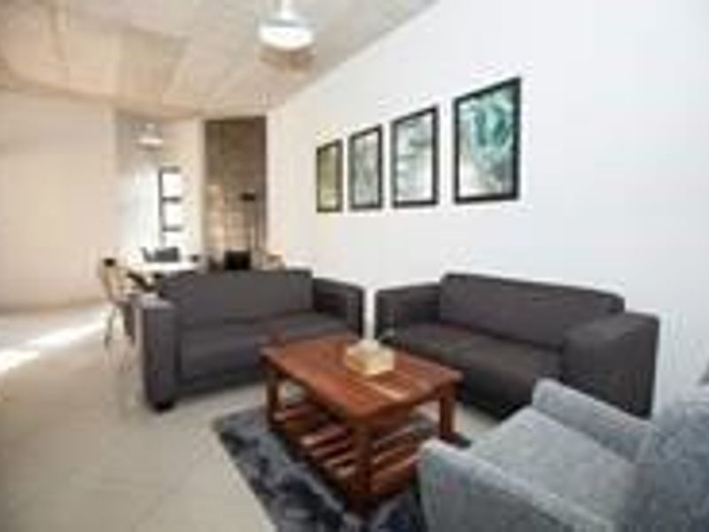 An open-plan living and dining area featuring neutral tiled flooring and recessed ceiling lighting, providing a versatile space for relaxation and meals.