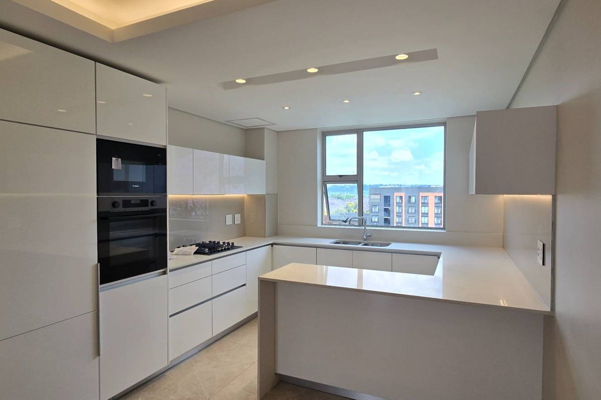 Modern kitchen featuring high-gloss cabinetry, integrated appliances, quartz countertops, and recessed lighting, offering a clean and contemporary aesthetic.