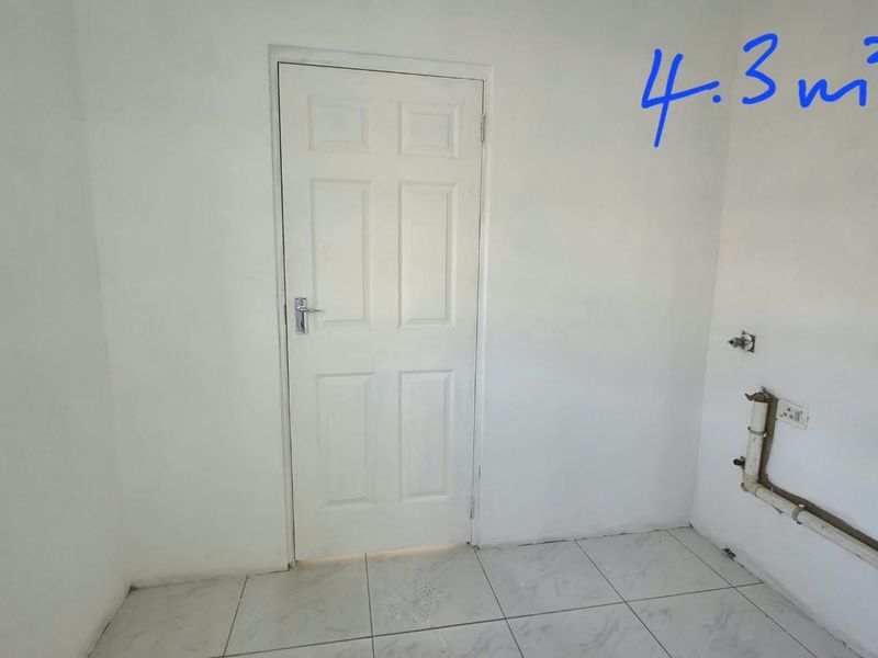 A small utility space featuring tiled flooring and exposed plumbing connections, suitable for laundry or storage purposes.