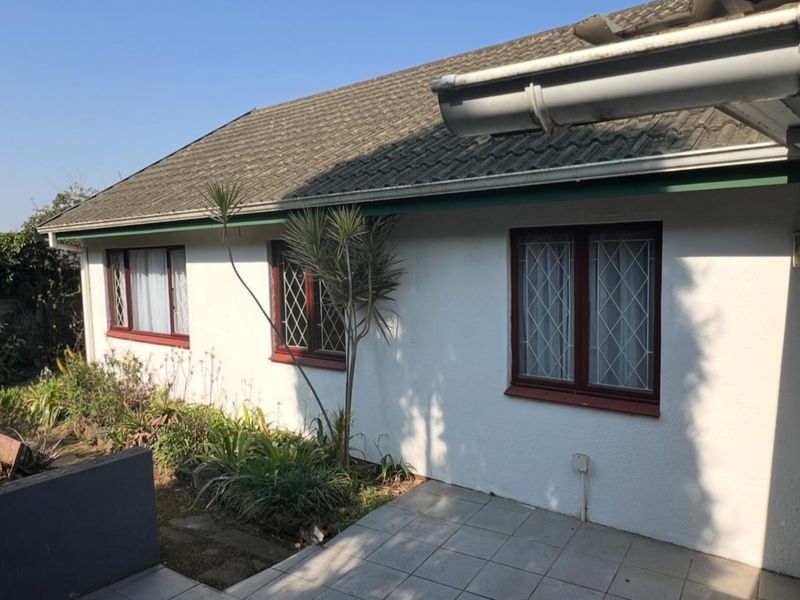 Rear exterior view of the townhouse featuring a tiled patio, plastered walls, and leaded glass windows under a pitched tiled roof.