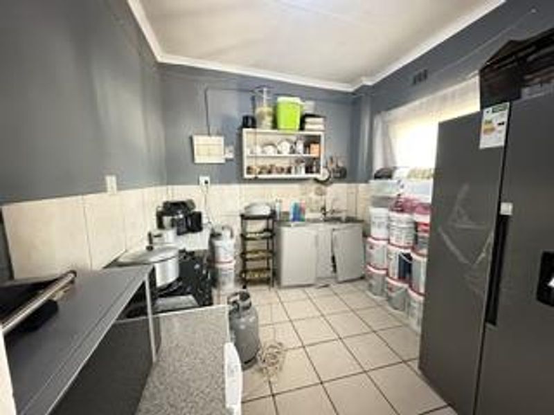 A functional kitchen space featuring tiled flooring, a tiled splashback, and built-in cabinetry, currently requiring some maintenance and cosmetic updates.