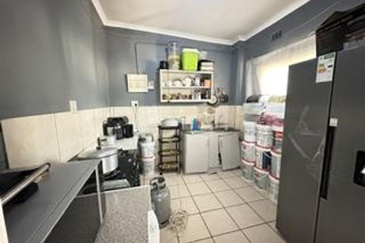 A functional kitchen space featuring tiled flooring, a tiled splashback, and built-in cabinetry, currently requiring some maintenance and cosmetic updates.