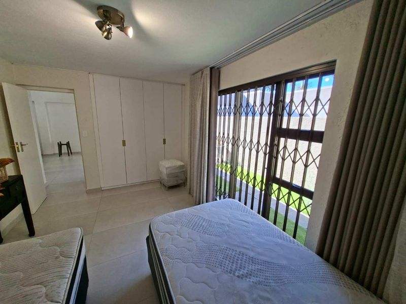 Bedroom featuring tiled flooring, built-in cupboards, and a sliding door with a security gate providing access to the exterior.