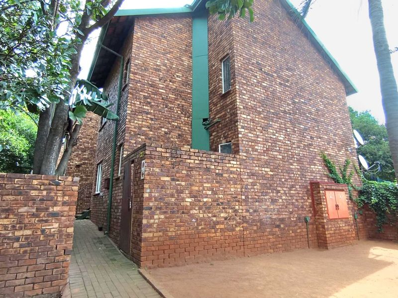 Rear view of a face brick apartment building featuring a paved walkway and utility access point.