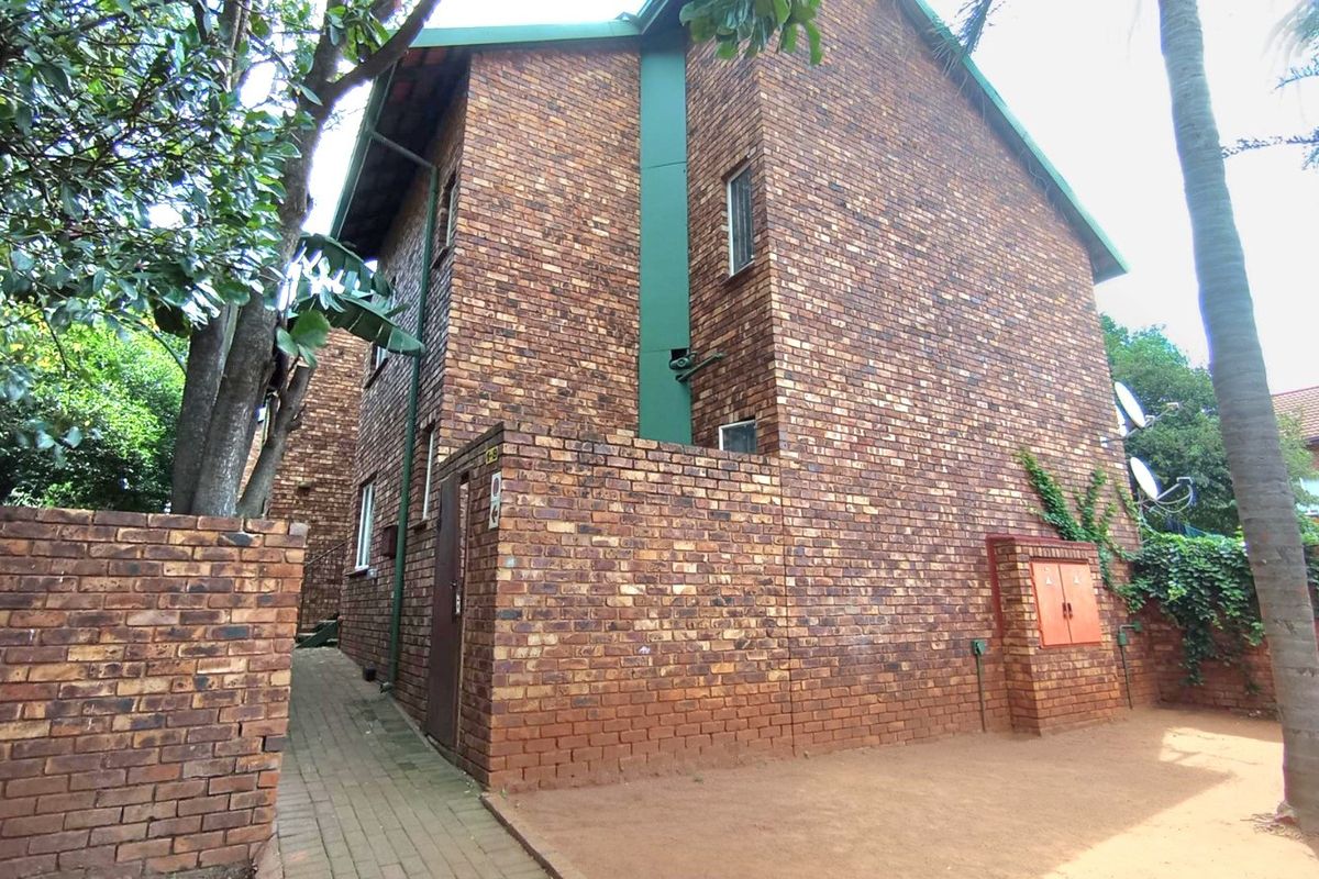 Rear view of a face brick apartment building featuring a paved walkway and utility access point.