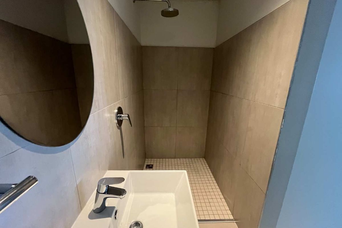 A modern bathroom featuring a walk-in shower with neutral wall tiles, a mosaic tiled shower floor, and a contemporary wall-mounted basin.