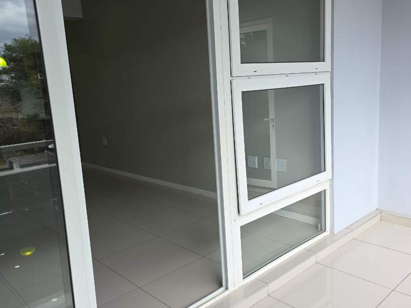 A clean, modern balcony area featuring white tiled flooring and high-quality aluminium framed sliding doors and windows.