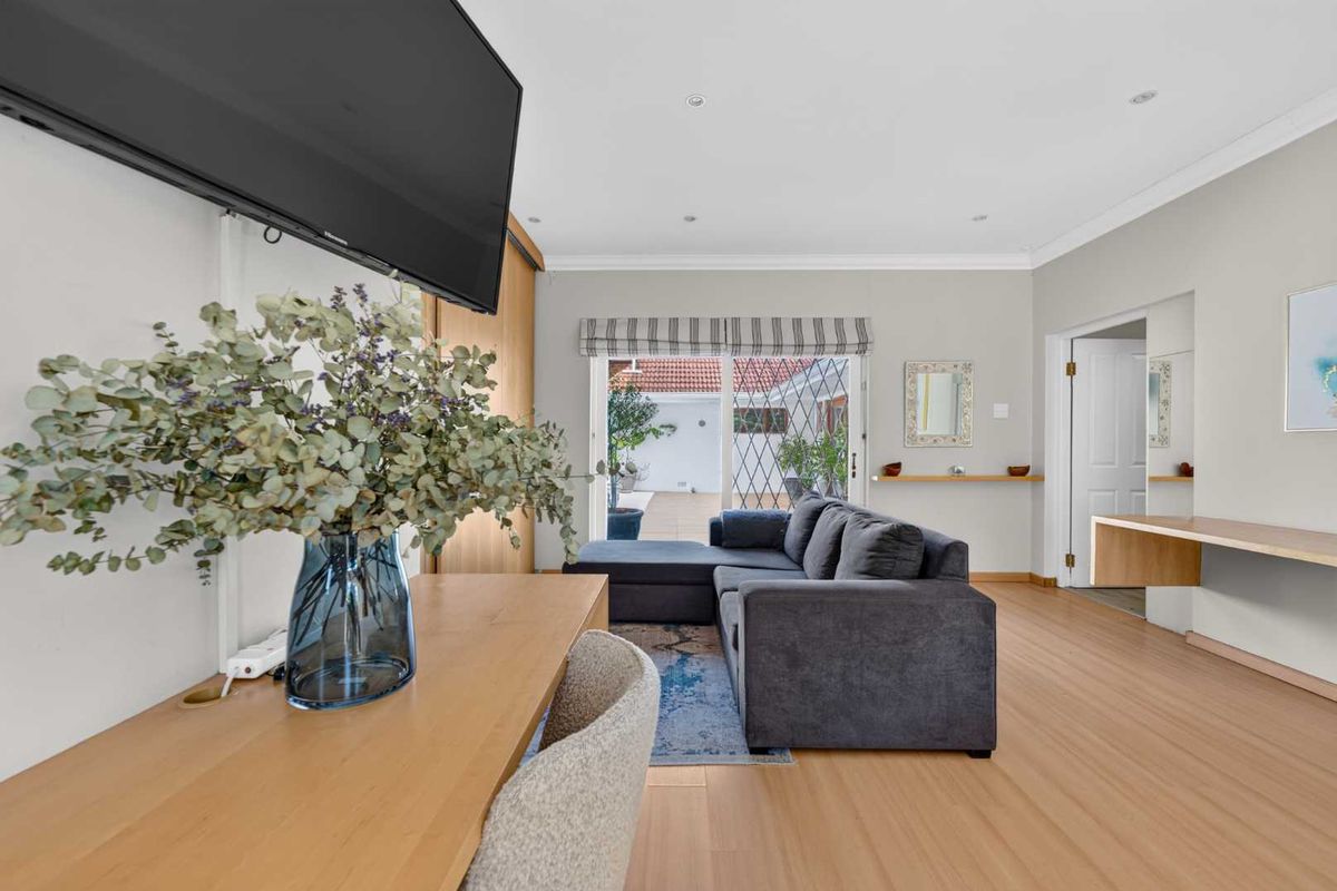 Bright living room featuring light laminate flooring, recessed lighting, and sliding glass doors providing direct access to the outdoor patio area.