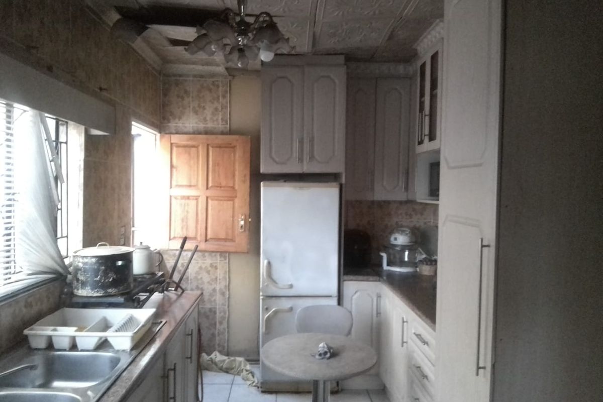 A dated kitchen featuring traditional cabinetry, tiled flooring, and a textured ceiling, requiring modernization to improve functionality and aesthetic appeal.