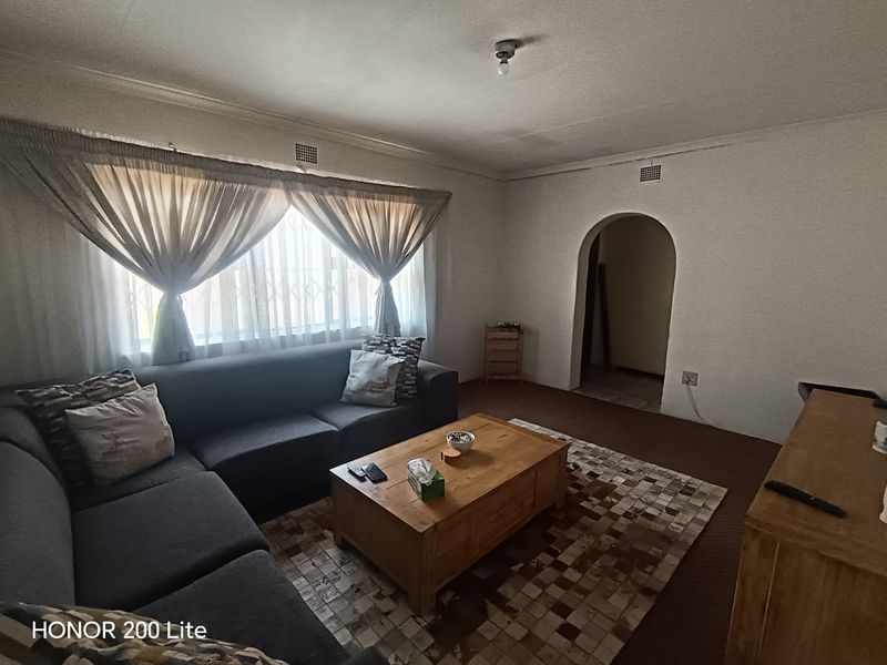 A living room featuring an arched doorway, security gate on the window, and ventilation grilles, providing a functional and traditional layout.