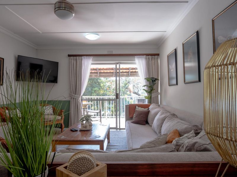 A comfortable living room featuring a ceiling fan, coving, and a sliding glass door that provides direct access to an outdoor balcony.