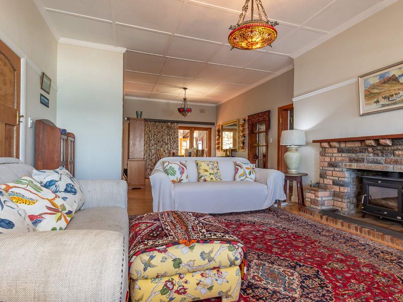 Spacious living room featuring a classic brick fireplace with a wood-burning stove and traditional tiled ceiling detail.