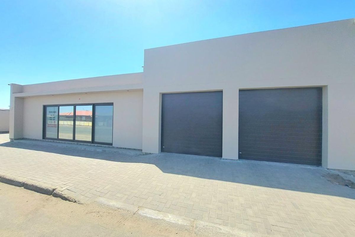 Modern exterior facade featuring a double garage with sectional doors and large sliding glass doors, set against a paved driveway.