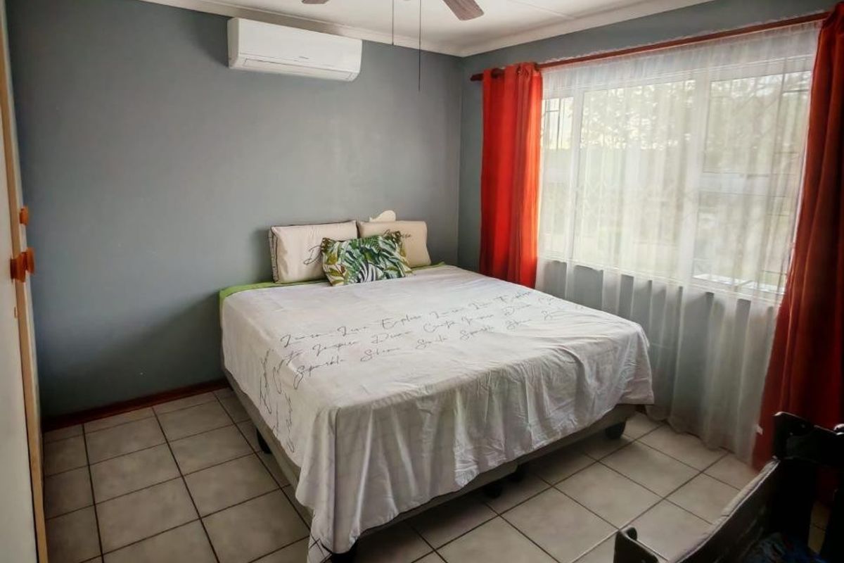 A bedroom featuring tiled flooring, a ceiling fan, and a wall-mounted split-system air conditioner.