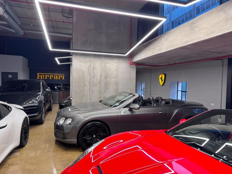 Modern industrial-style garage space featuring exposed concrete structural elements, polished concrete floors, and contemporary linear LED lighting.