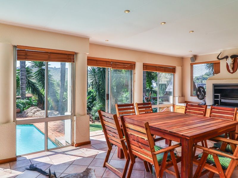Spacious covered patio featuring a built-in braai, tiled flooring, and large sliding glass doors providing direct access to the pool area.