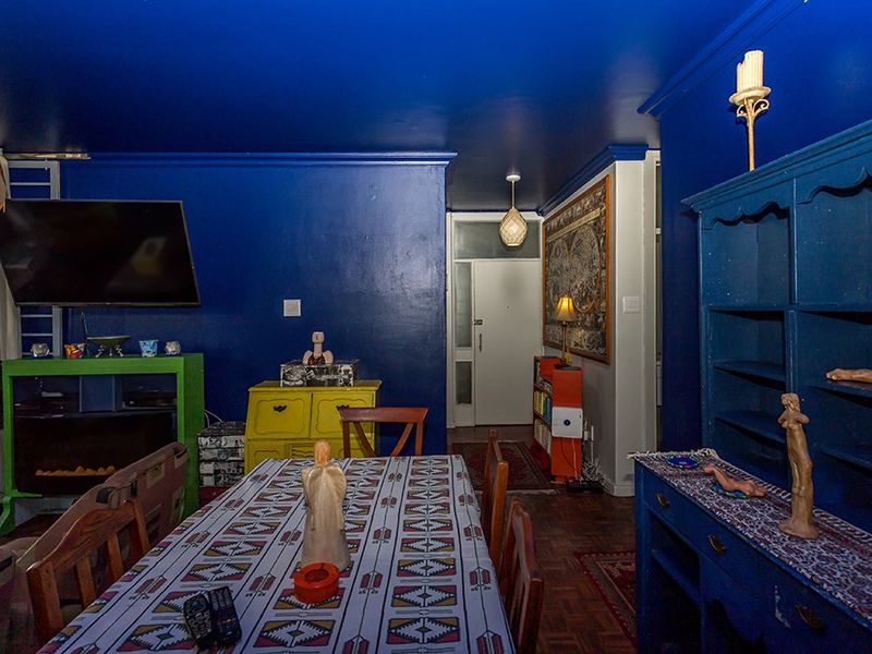 A living area featuring dark blue painted walls and ceiling, parquet flooring, and integrated lighting fixtures, providing a distinct and bold interior space.