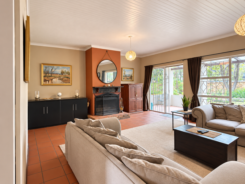 Spacious living room featuring a central fireplace, terracotta tiled flooring, and sliding glass doors providing direct access to the outdoor patio area.