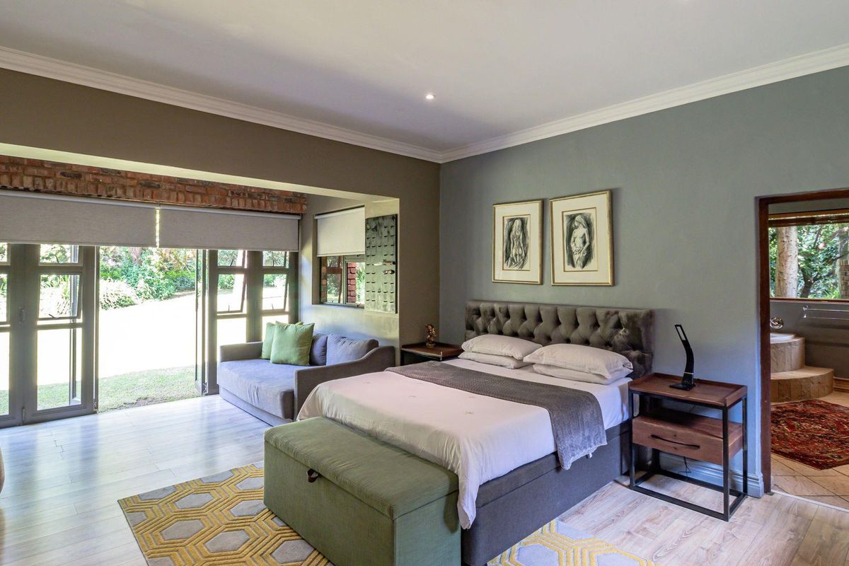 Spacious bedroom featuring laminate flooring, coving, and bi-fold doors opening to the garden, with an adjoining en-suite bathroom.