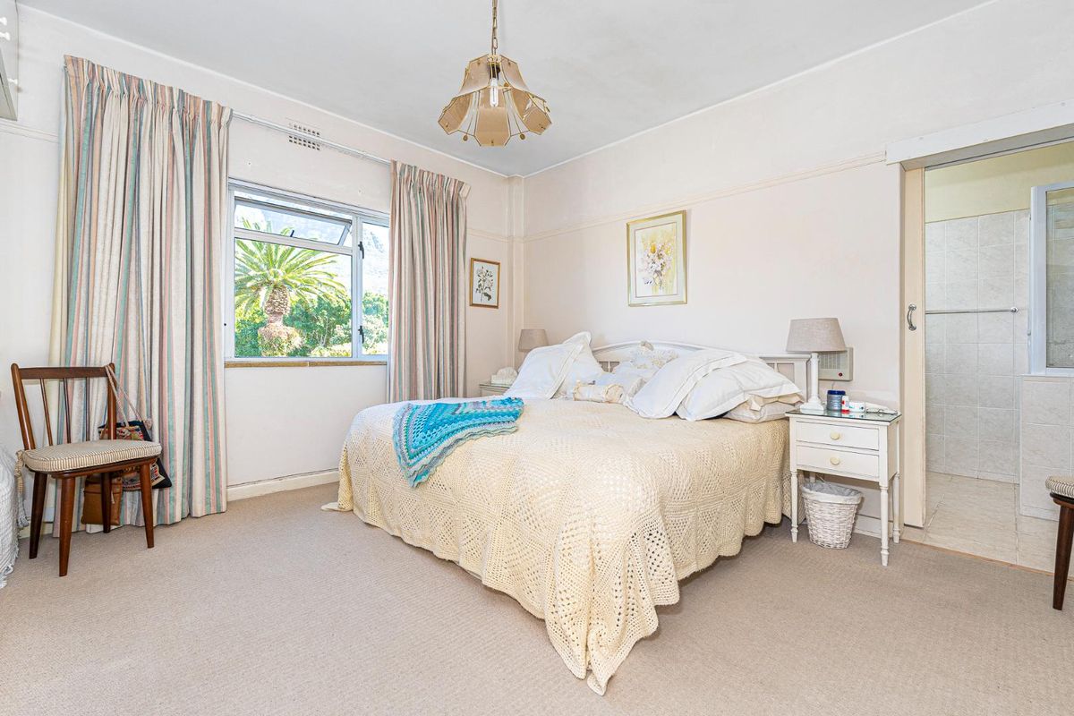 A well-proportioned bedroom featuring a picture rail, casement window, and an adjoining en-suite bathroom.