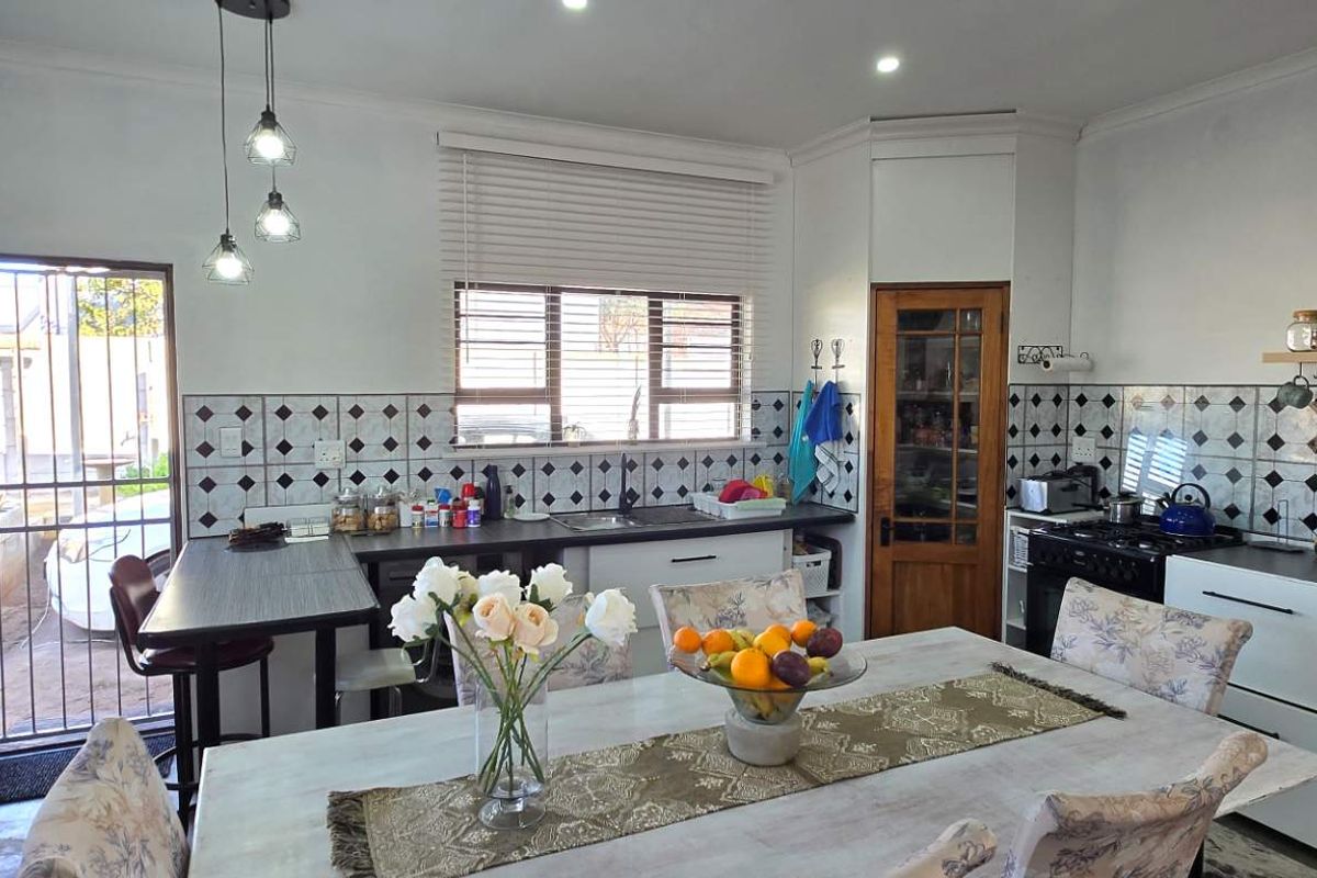 A functional kitchen featuring a tiled backsplash, built-in cabinetry, and a dedicated dining area with direct access to the exterior.