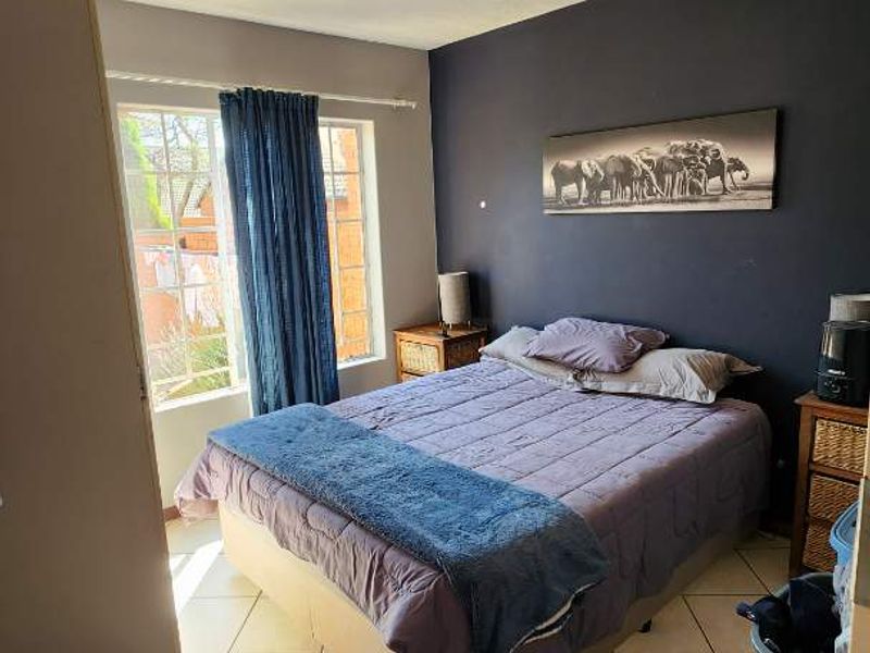 A bedroom featuring tiled flooring, a central ceiling light fixture, and a window allowing natural light into the space.