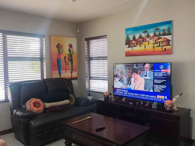 A comfortable living room featuring tiled flooring, recessed downlighting, and venetian blinds on the windows.