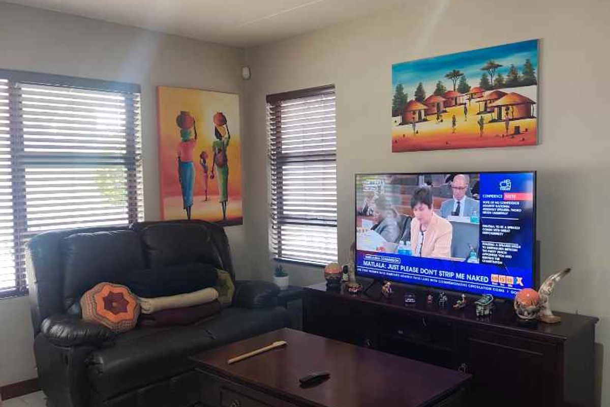 A comfortable living room featuring tiled flooring, recessed downlighting, and venetian blinds on the windows.