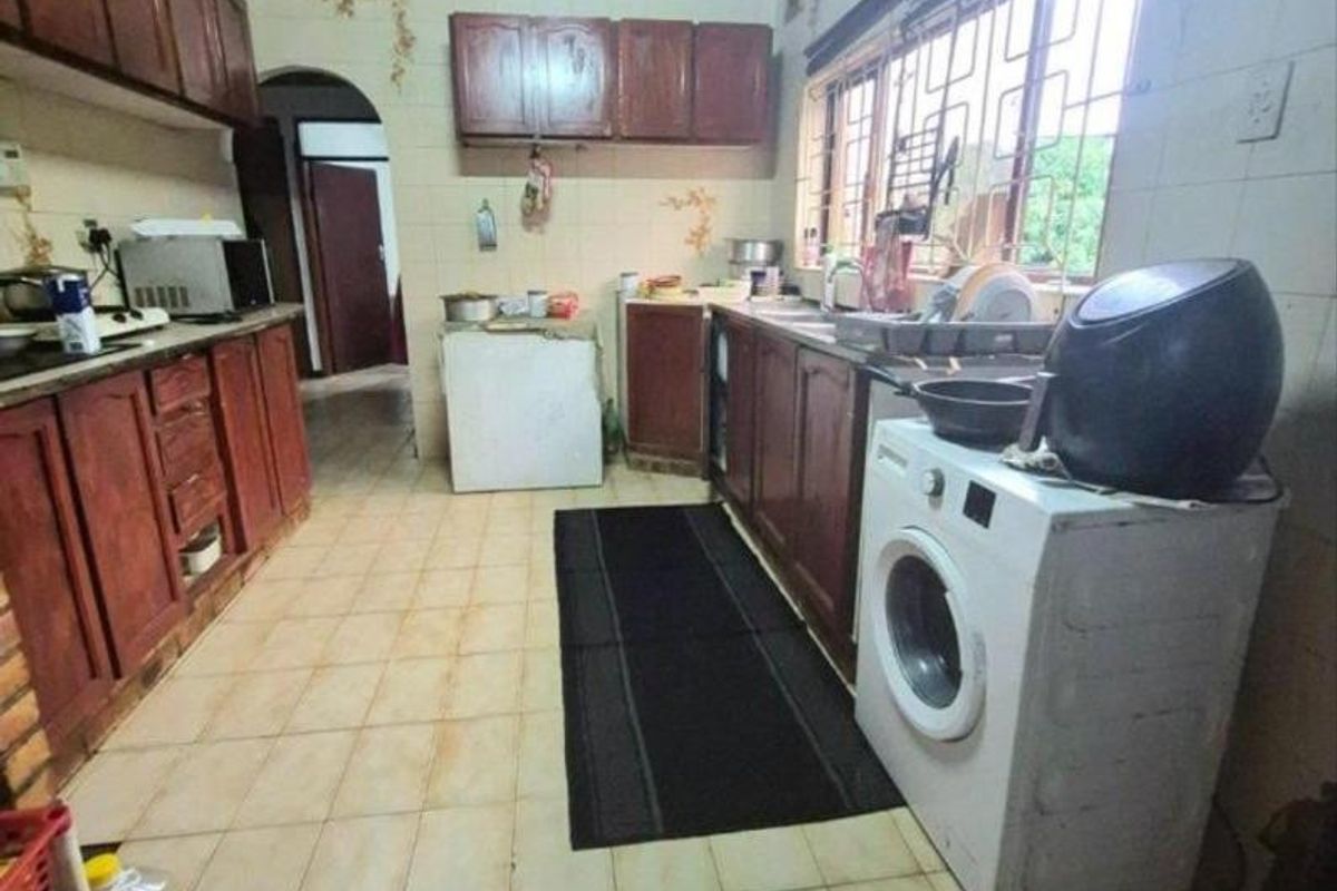 A dated kitchen featuring wooden cabinetry, tiled flooring, and a tiled splashback, requiring cosmetic updates to modernize the space.