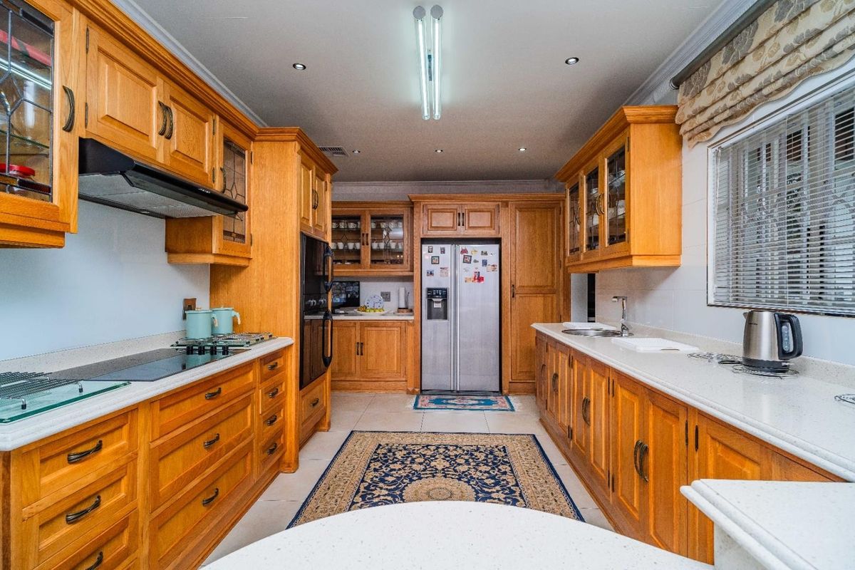 A well-maintained kitchen featuring extensive wooden cabinetry, stone countertops, integrated appliances, and recessed lighting, offering a classic and functional workspace.