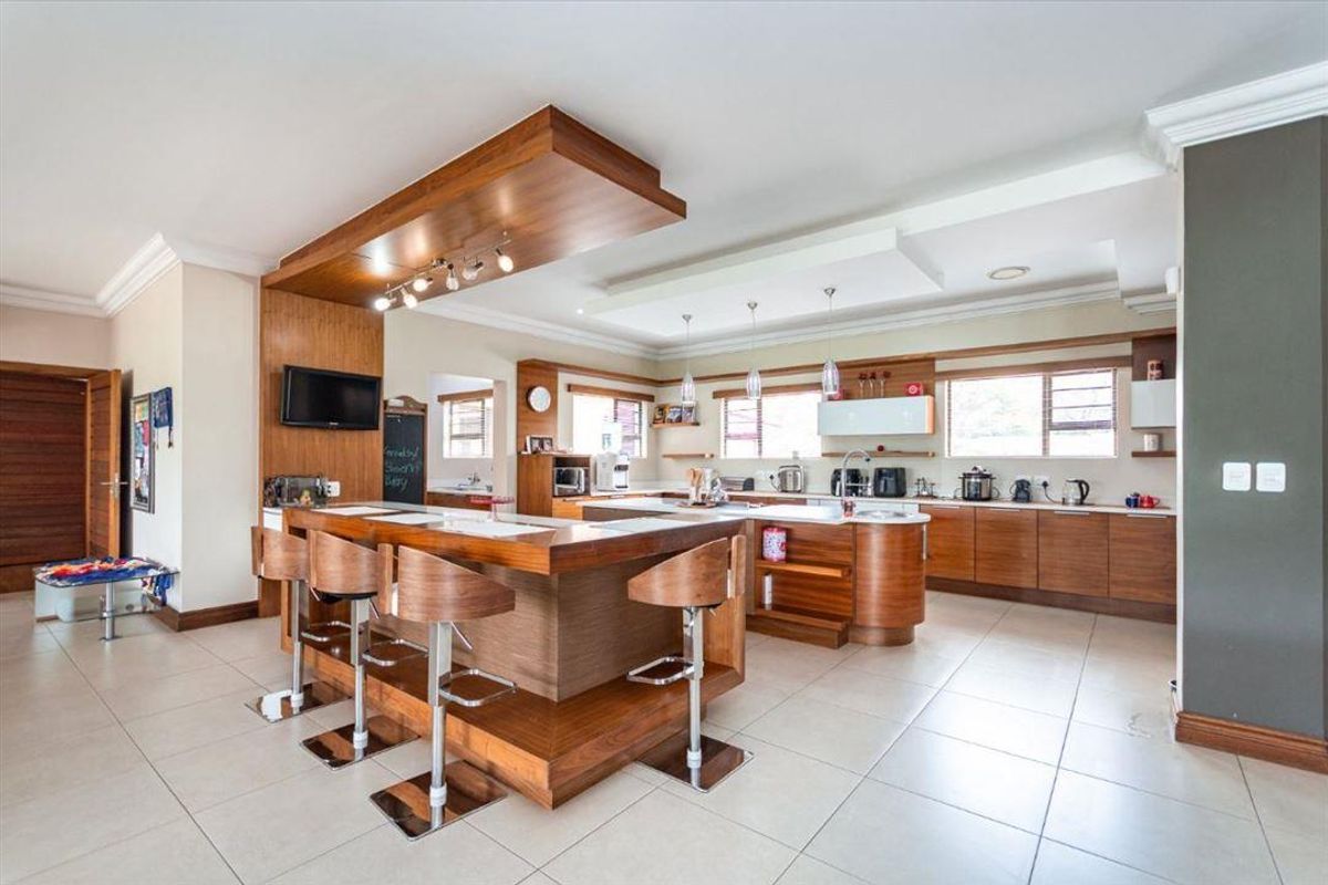 Spacious modern kitchen featuring extensive wooden cabinetry, a large central island with a breakfast bar, and integrated lighting.