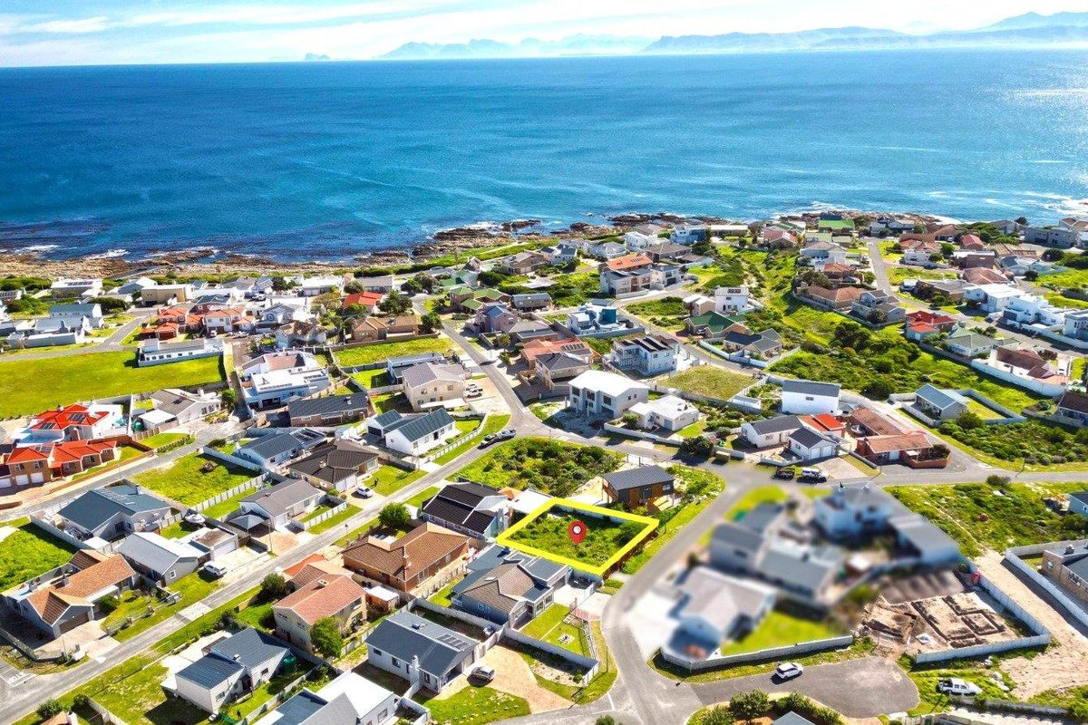 An aerial view of a vacant residential plot located in a coastal neighborhood, highlighting its proximity to the ocean and surrounding residential development.