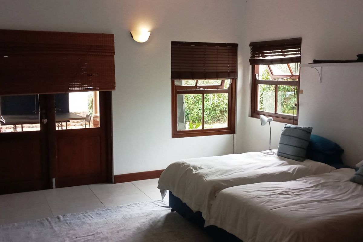 A bedroom featuring tiled flooring, wooden window frames, and a wooden door leading to an outdoor area.