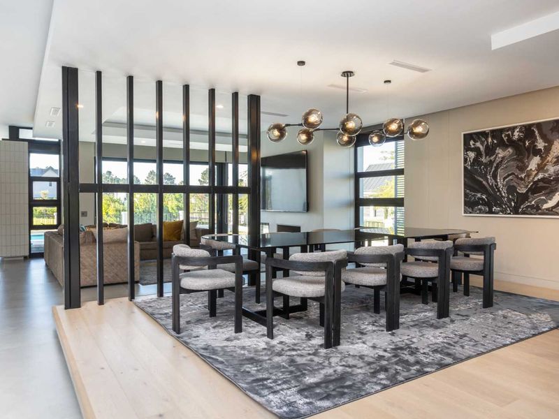 Modern open-plan dining area featuring a striking metal room divider, contemporary chandelier, and a seamless transition between timber and tiled flooring.