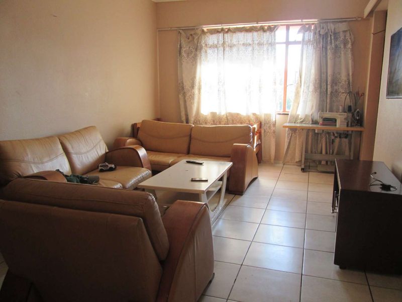 A living room featuring tiled flooring and a large window, providing natural light to the space.