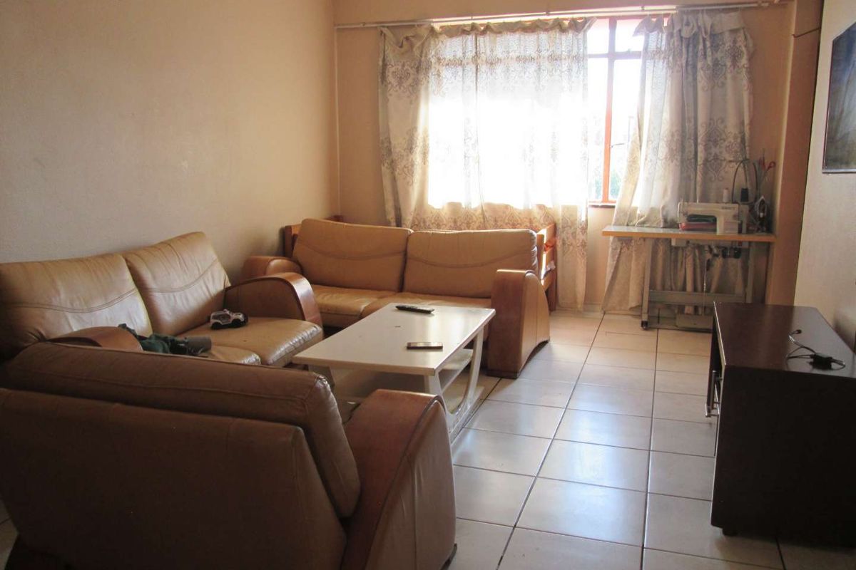 A living room featuring tiled flooring and a large window, providing natural light to the space.
