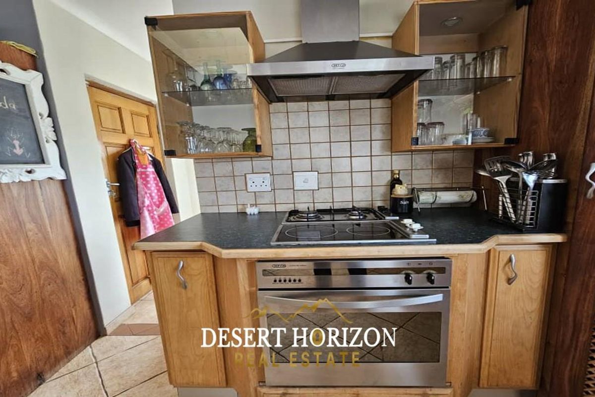 A functional kitchen featuring wooden cabinetry, a built-in oven, gas hob, stainless steel extractor fan, and tiled backsplash.
