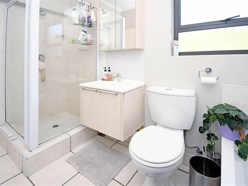 A functional bathroom featuring a glass-enclosed shower, a wall-mounted vanity with basin, a mirrored medicine cabinet, and tiled flooring.