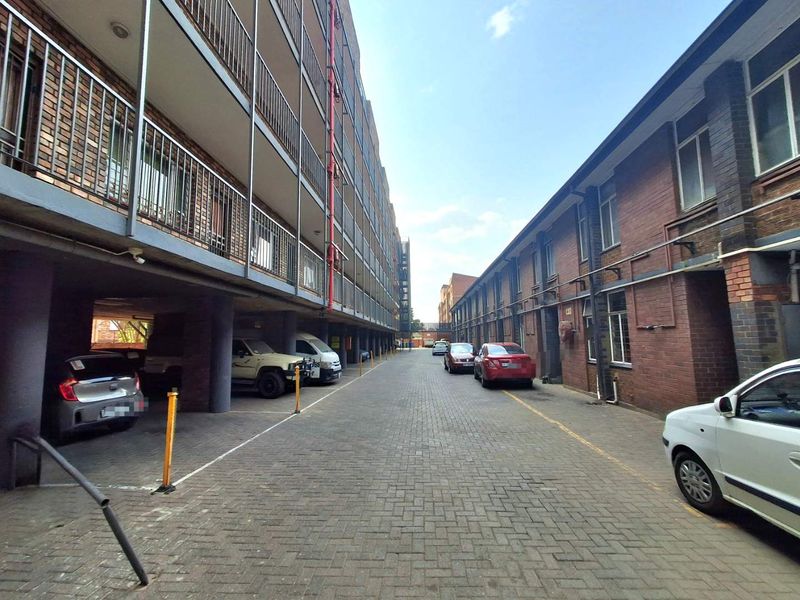 View of the apartment complex exterior showing the paved driveway, brick building facades, and metal balcony railings.