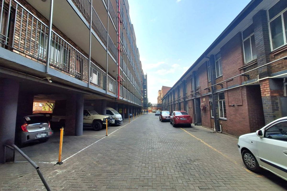 View of the apartment complex exterior showing the paved driveway, brick building facades, and metal balcony railings.