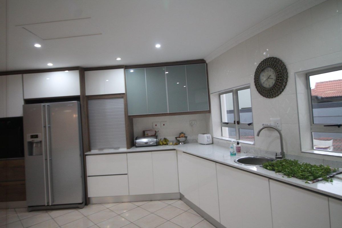Modern kitchen featuring white cabinetry, stone countertops, integrated sink, and recessed ceiling lighting.