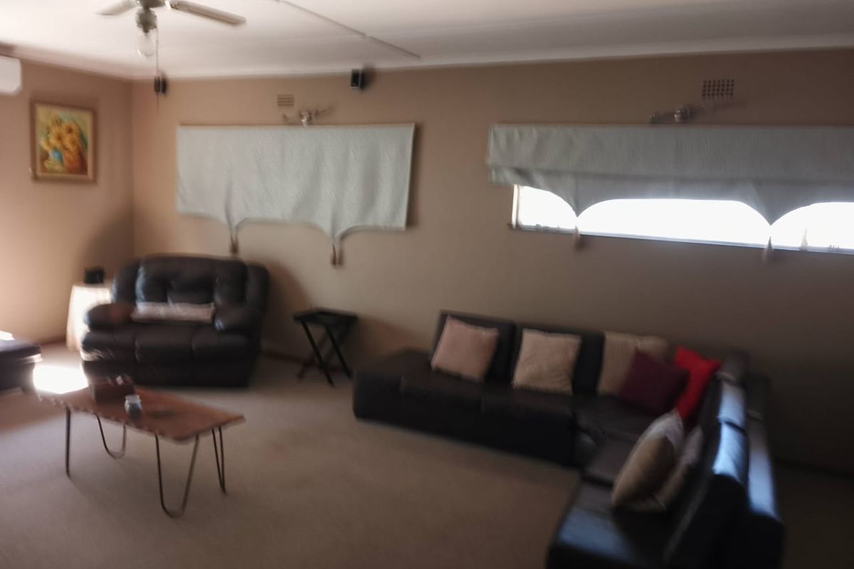 A spacious living room featuring a ceiling fan and wall-mounted lighting, providing a comfortable area for relaxation.