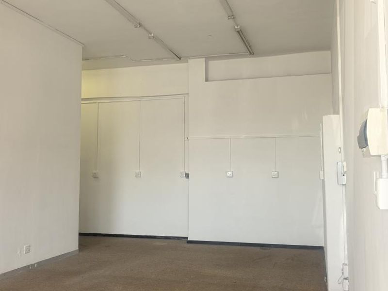 An empty, open-plan commercial office space featuring neutral walls, carpeted flooring, and integrated strip lighting, suitable for various business configurations.