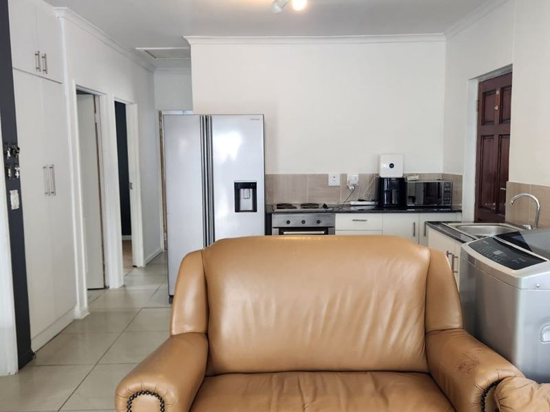 Open plan living area featuring tiled floors, built-in kitchen cabinetry with integrated oven and hob, and direct access to adjacent rooms.