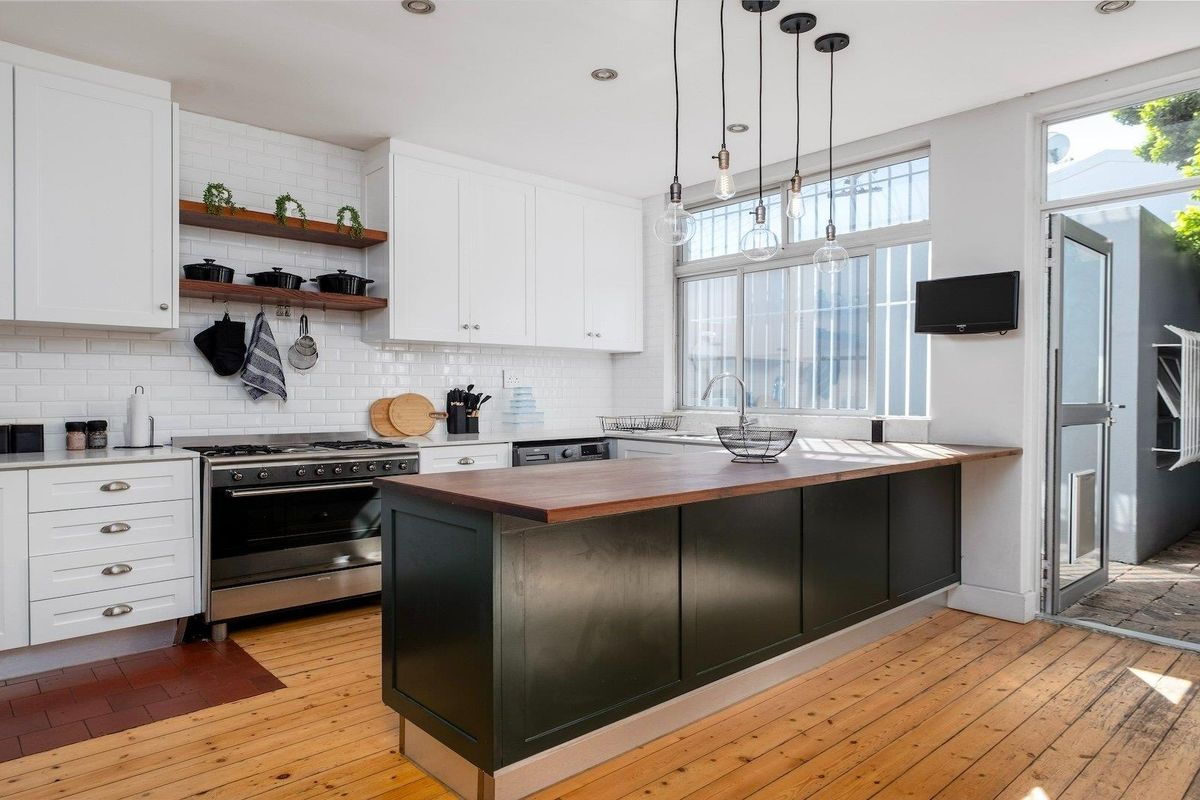 Modern kitchen featuring a central island with a wooden countertop, white cabinetry, subway tile backsplash, and direct access to an outdoor area.