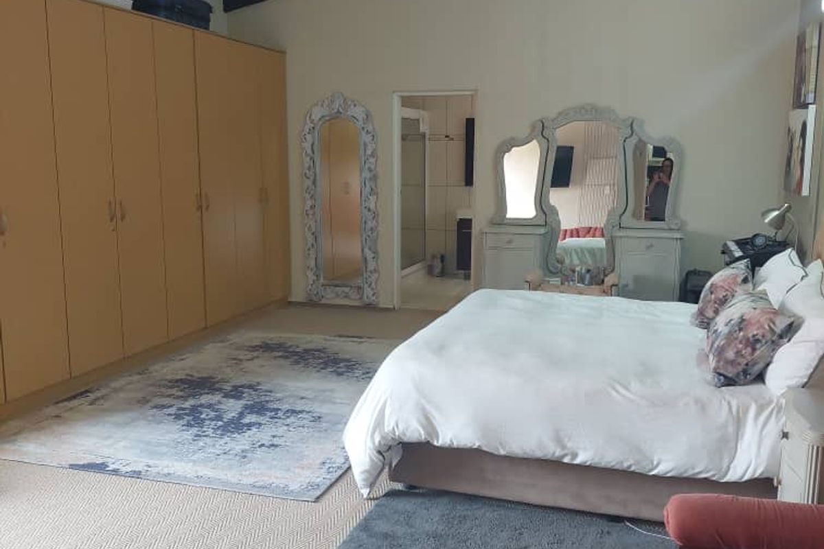 Spacious bedroom featuring high vaulted ceilings with a ceiling fan and extensive built-in cabinetry, with an adjoining en-suite bathroom.