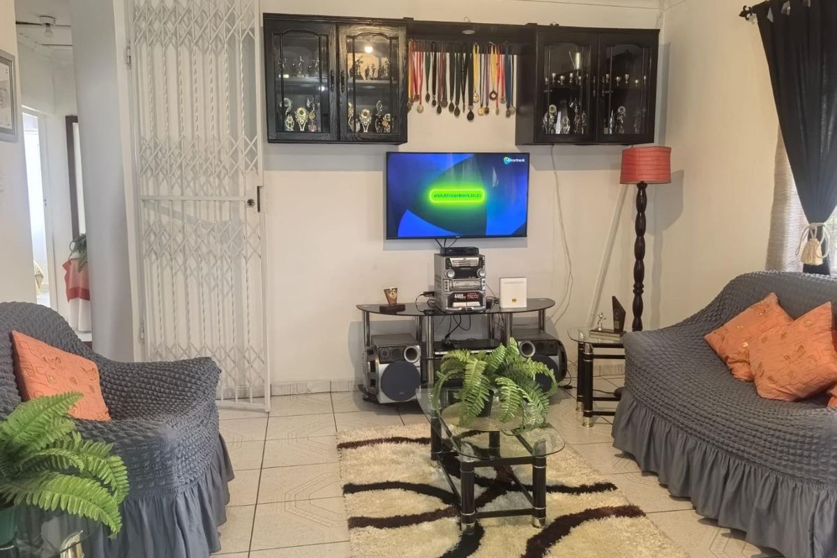 A living room featuring ceramic floor tiles, a security gate, and built-in wall cabinetry for storage and display.